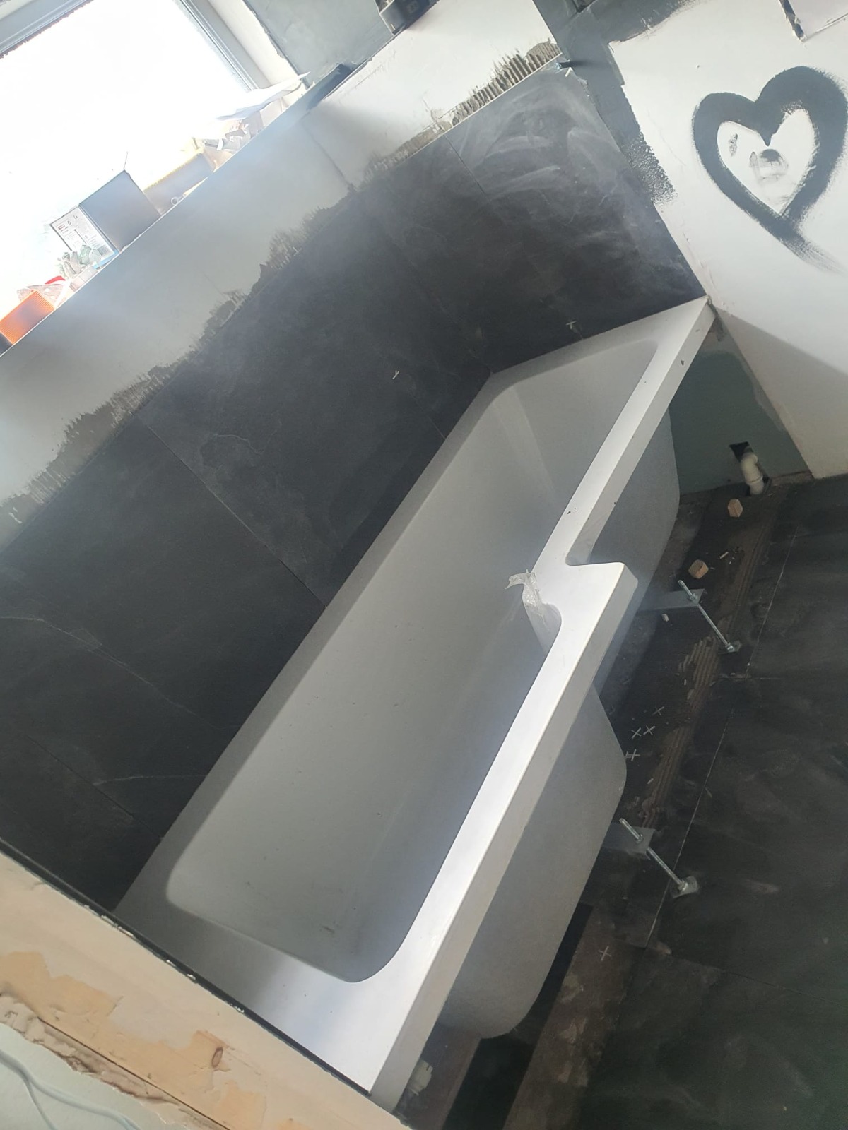 New bath tub being fitted with painted black bath panel — South Wales bathroom